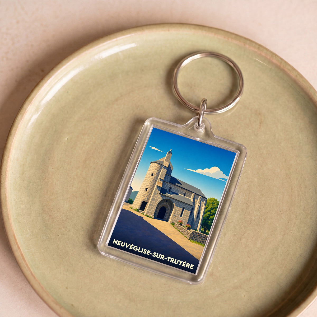 Porte-clés souvenir de la ville de Neuvéglise-sur-Truyère avec une illustration stylisée de son église.
