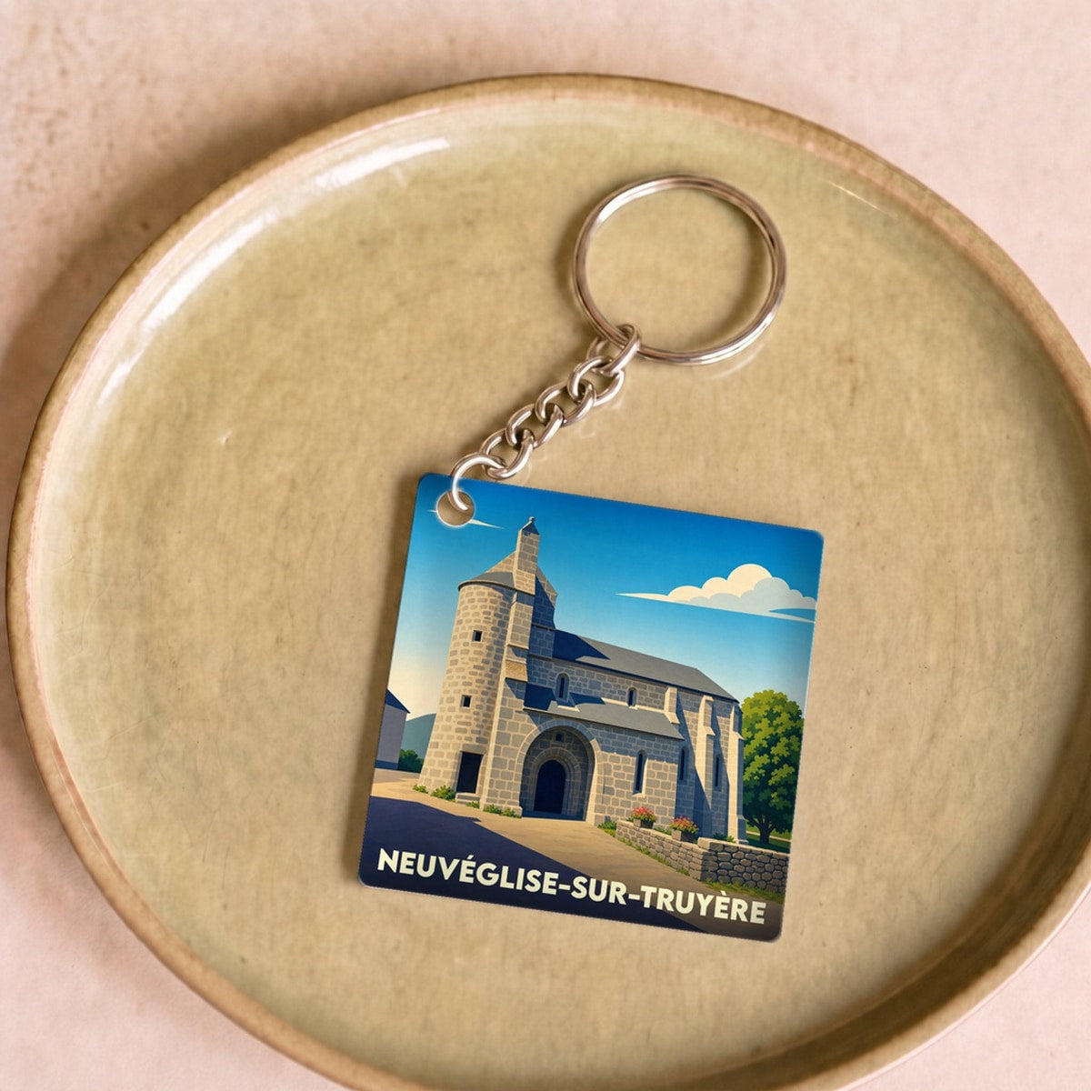 Porte-clés souvenir de la ville de Neuvéglise-sur-Truyère avec une illustration stylisée de son église.