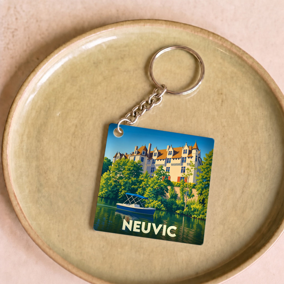 Porte-clés souvenir de la ville de Neuvic avec une illustration stylisée d'un château au bord de l'eau.
