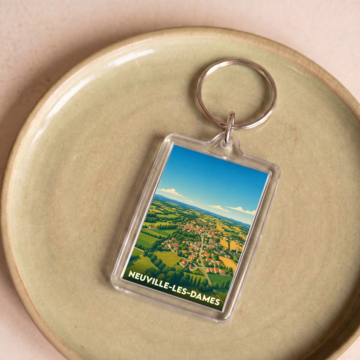 Porte-clés souvenir de la ville de Neuville-les-Dames avec une illustration stylisée.