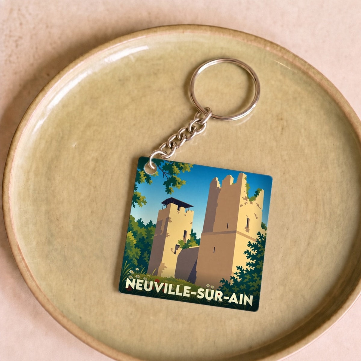 Porte-clés souvenir de la ville de Neuville-sur-Ain avec une illustration stylisée.