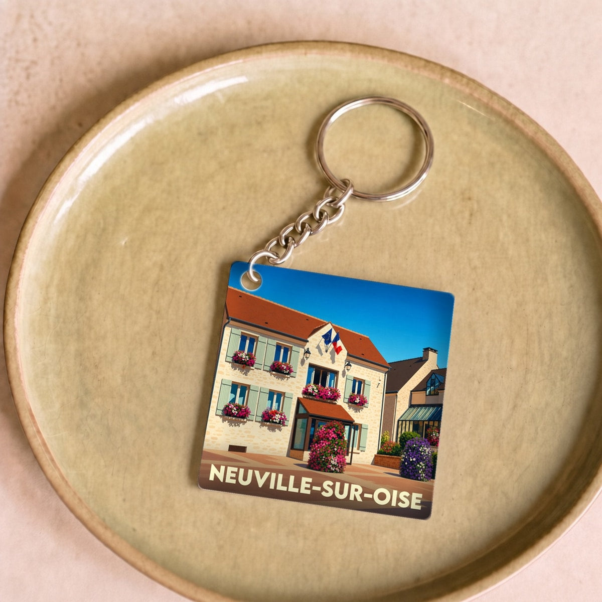 Porte-clés souvenir de la ville de Neuville-sur-Oise avec une illustration stylisée de sa mairie.