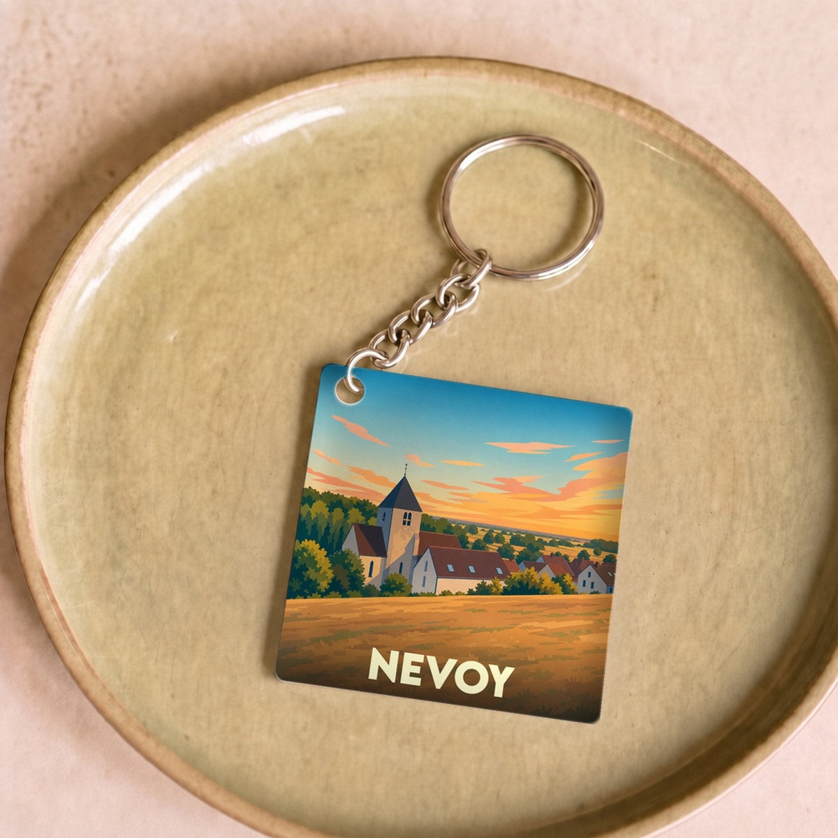 Porte-clés souvenir de la ville de Nevoy avec une illustration stylisée d'un paysage rural au coucher du soleil.