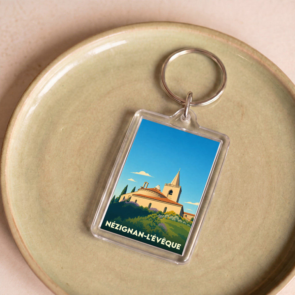 Porte-clés souvenir de la ville de Nézignan-l'Évêque avec une illustration stylisée de son église.