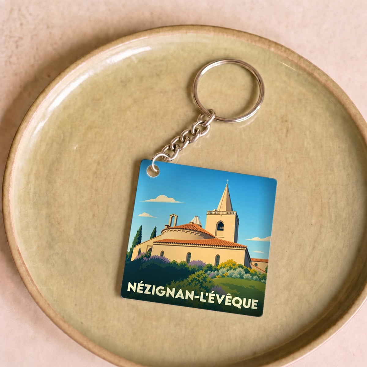 Porte-clés souvenir de la ville de Nézignan-l'Évêque avec une illustration stylisée de son église.