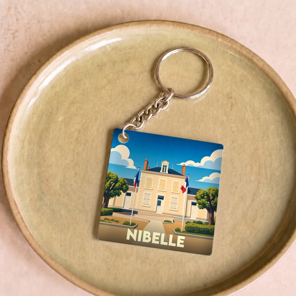 Porte-clés souvenir de la ville de Nibelle avec une illustration stylisée de sa mairie.