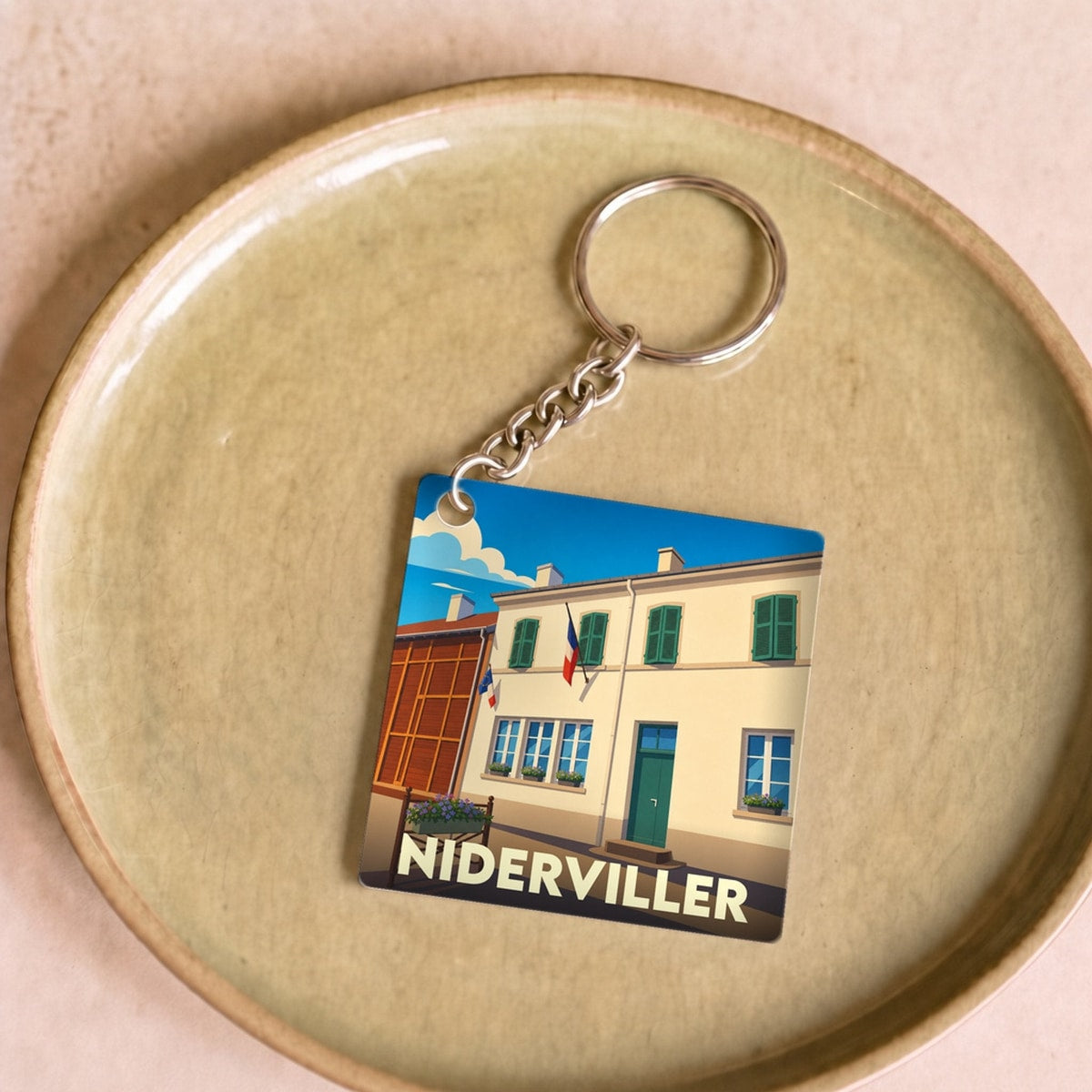 Porte-clés souvenir de la ville de Niderviller avec une illustration stylisée d'un bâtiment typique.