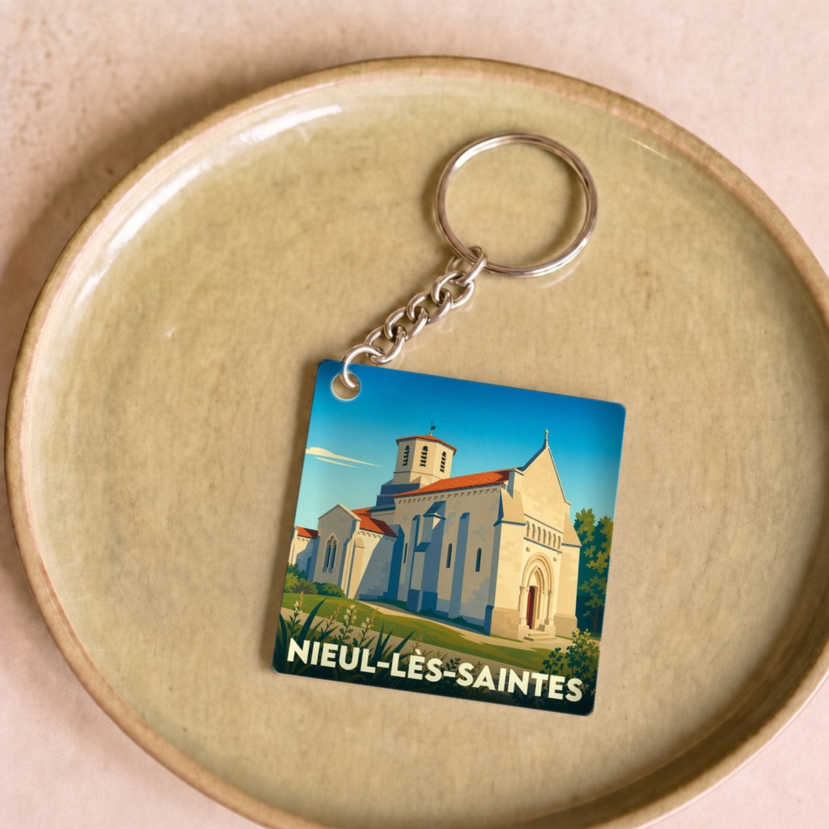 Porte-clés souvenir de la ville de Nieul-lès-Saintes avec une illustration stylisée de son église.