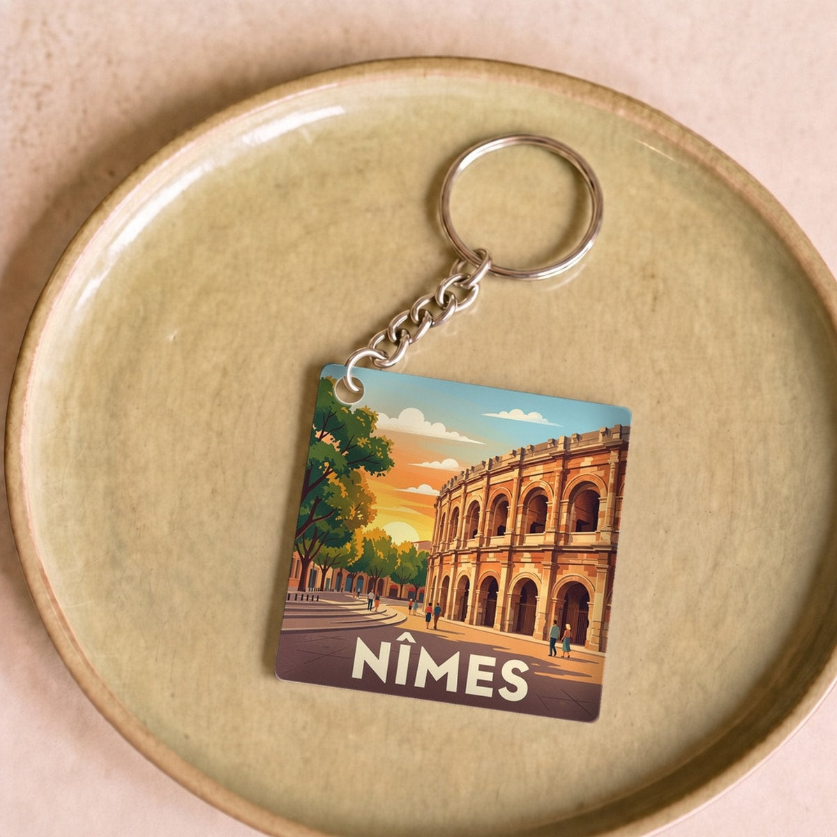 Porte-clés souvenir de la ville de Nîmes avec une illustration stylisée de ses arènes romaines.