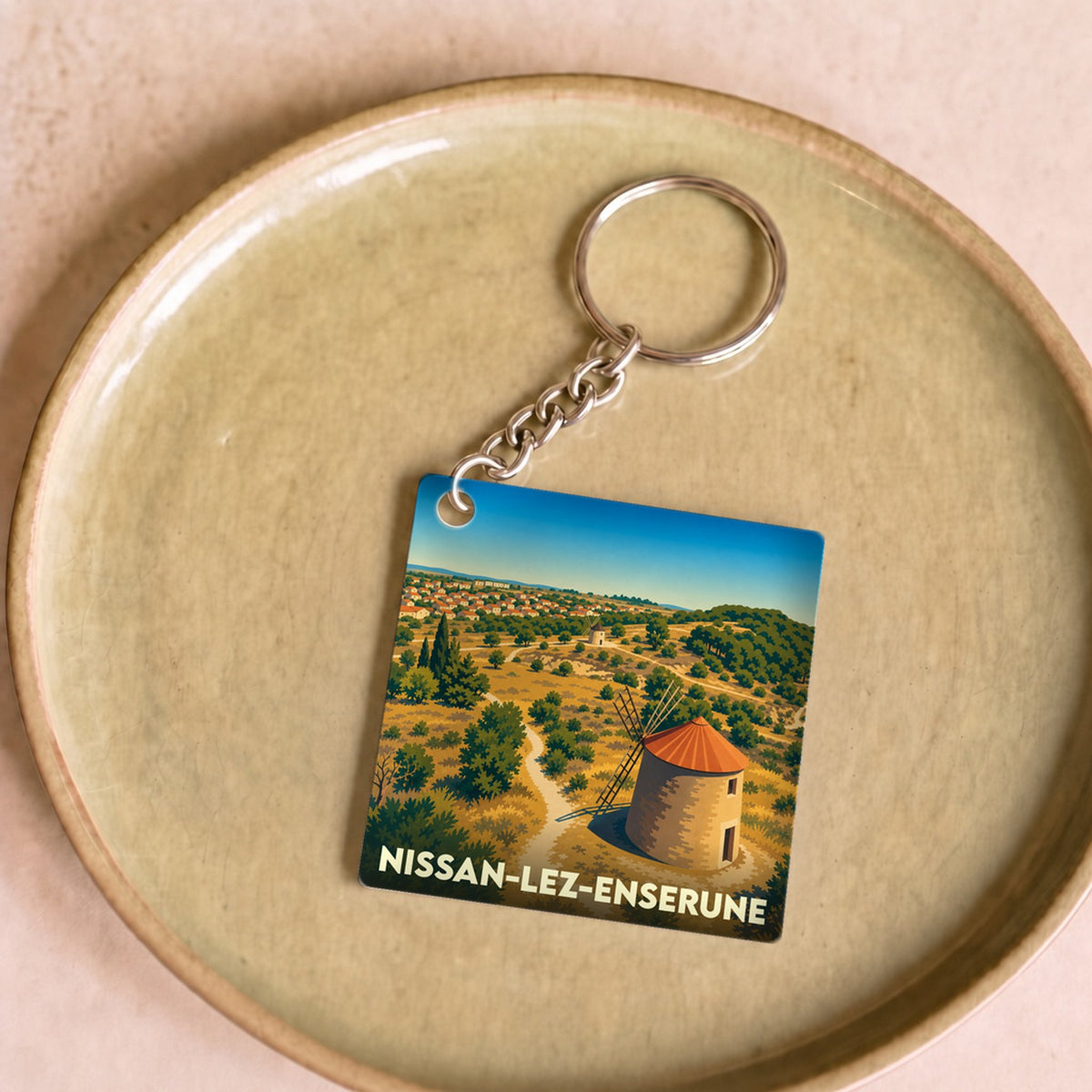 Porte-clés souvenir de la ville de Nissan-lez-Enserune avec une illustration stylisée d'un moulin.