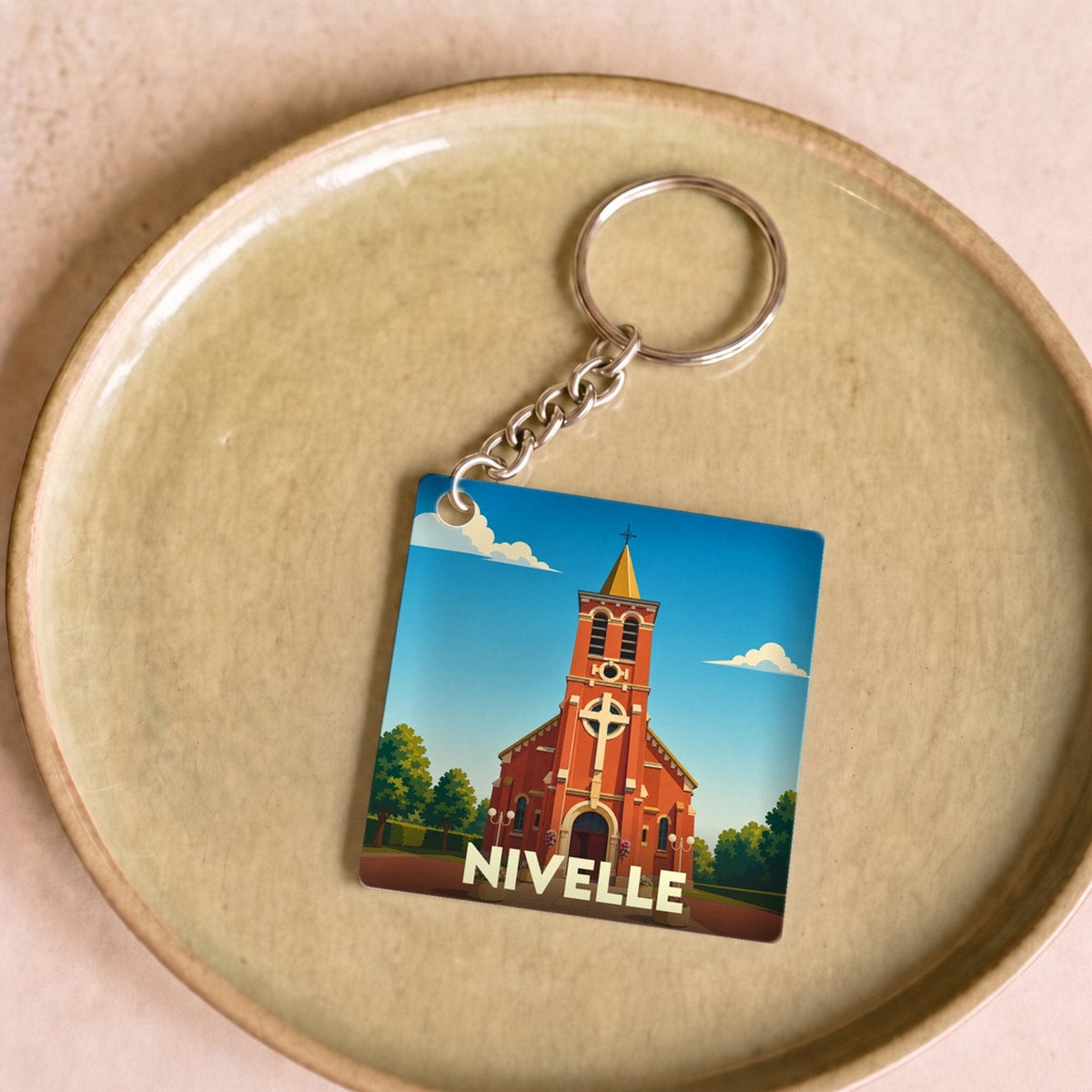Porte-clés souvenir de la ville de Nivelle avec une illustration stylisée de son église.