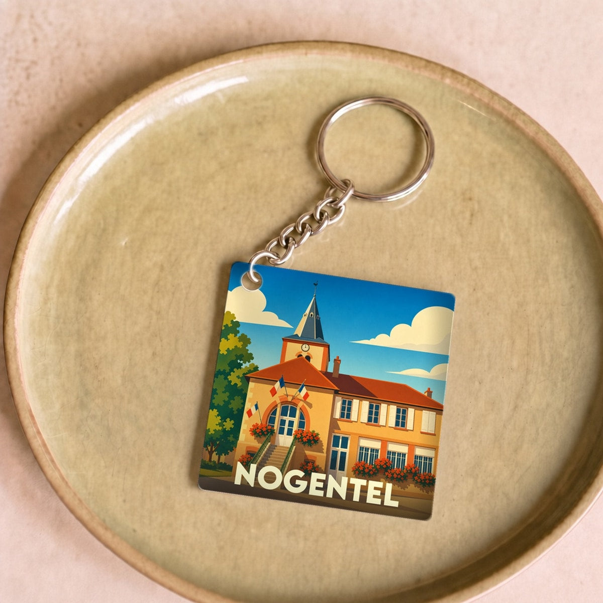 Porte-clés souvenir de la ville de Nogentel avec une illustration stylisée de sa mairie.