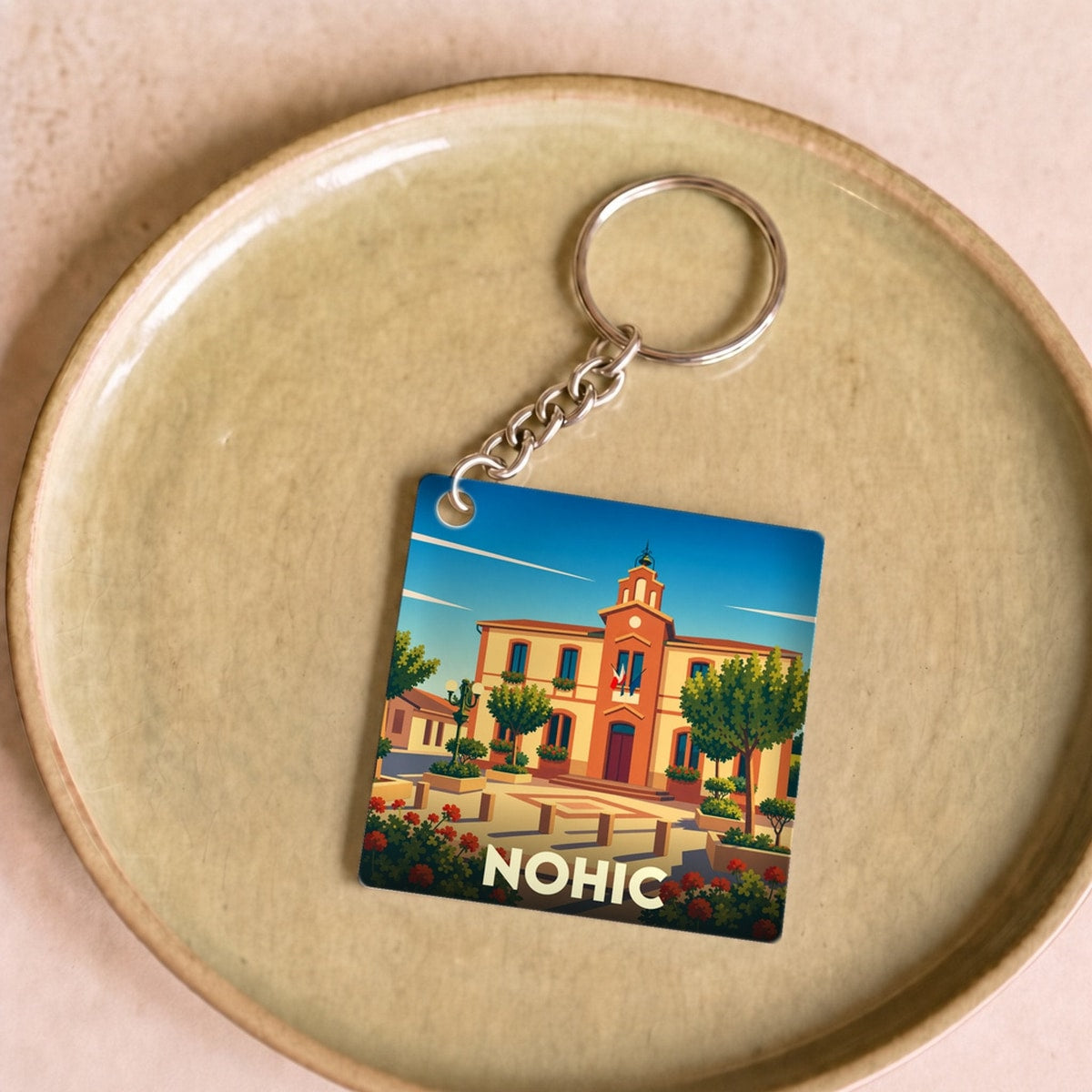 Porte-clés souvenir de la ville de Nohic avec une illustration stylisée de sa mairie.