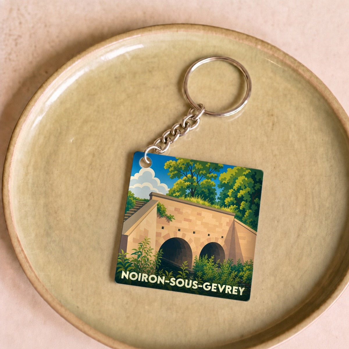 Porte-clés souvenir de Noiron-sous-Gevrey avec une illustration stylisée d'un pont en pierre.