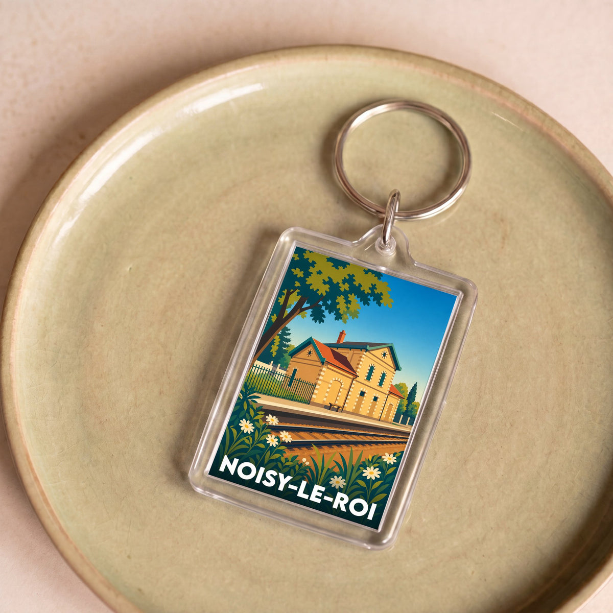 Porte-clés souvenir de la ville de Noisy-le-Roi avec une illustration stylisée de sa gare.