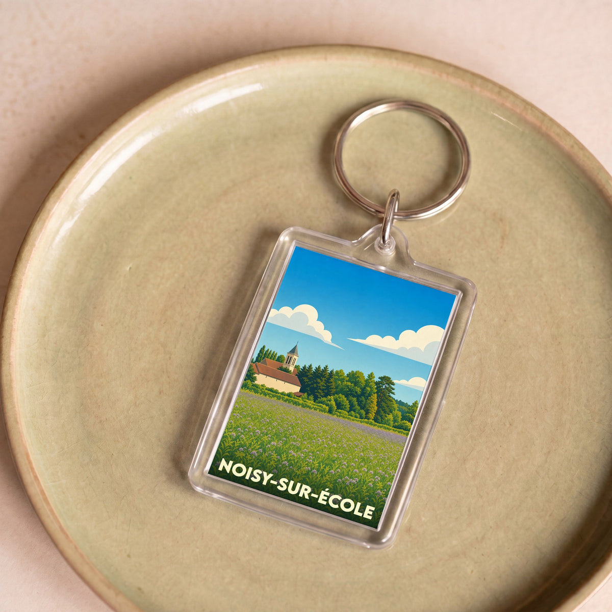 Porte-clés souvenir de la ville de Noisy-sur-École avec une illustration stylisée de son paysage rural.