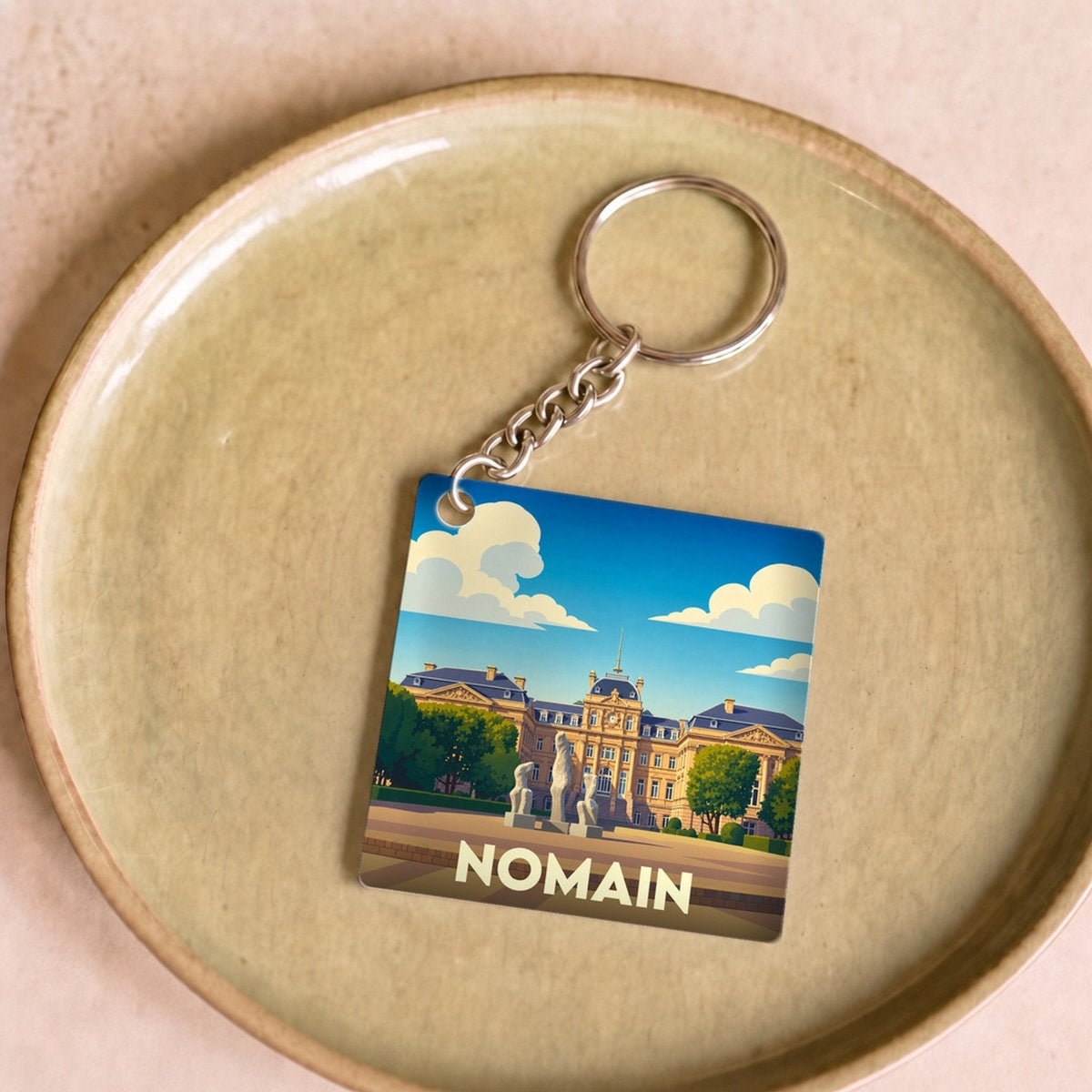 Porte-clés souvenir de la ville de Nomain avec une illustration stylisée.