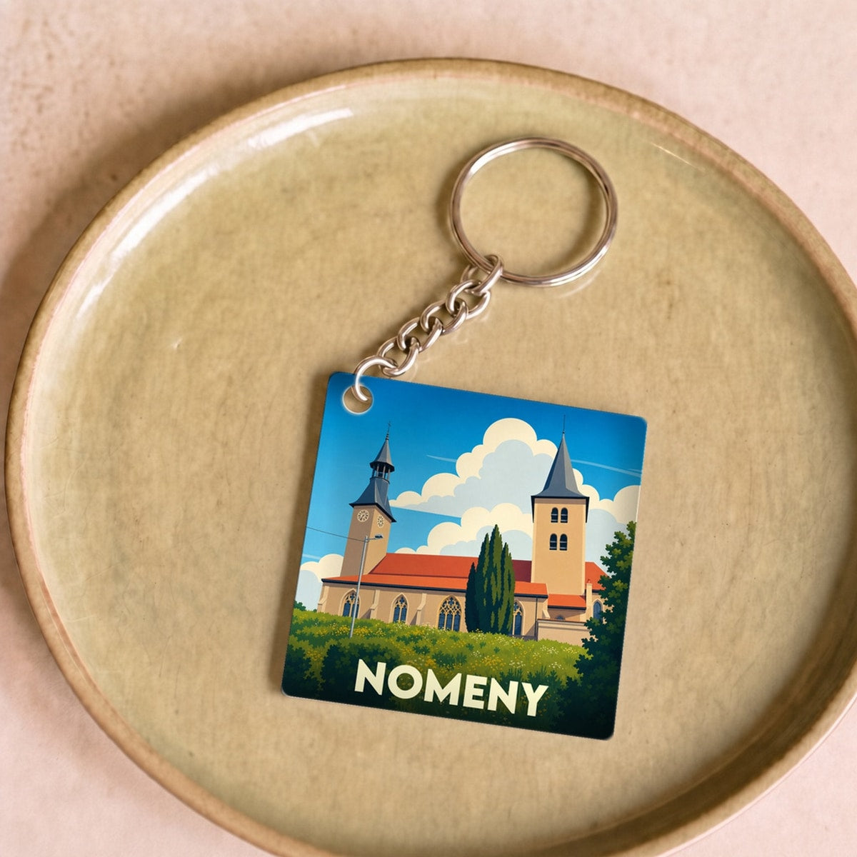 Porte-clés souvenir de la ville de Nomeny avec une illustration stylisée de son église.
