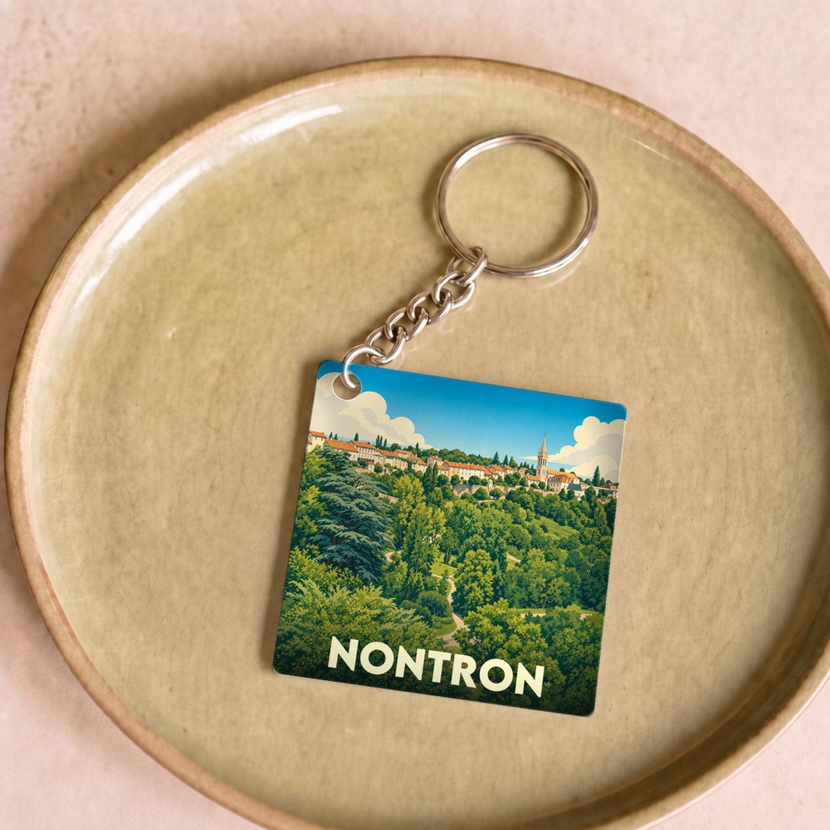 Porte-clés souvenir de la ville de Nontron avec une illustration stylisée de son paysage arboré.