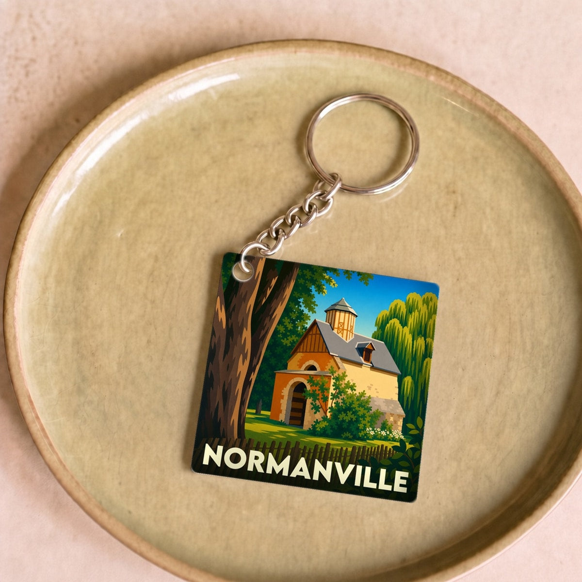Porte-clés souvenir de la ville de Normanville avec une illustration stylisée d'un bâtiment historique.