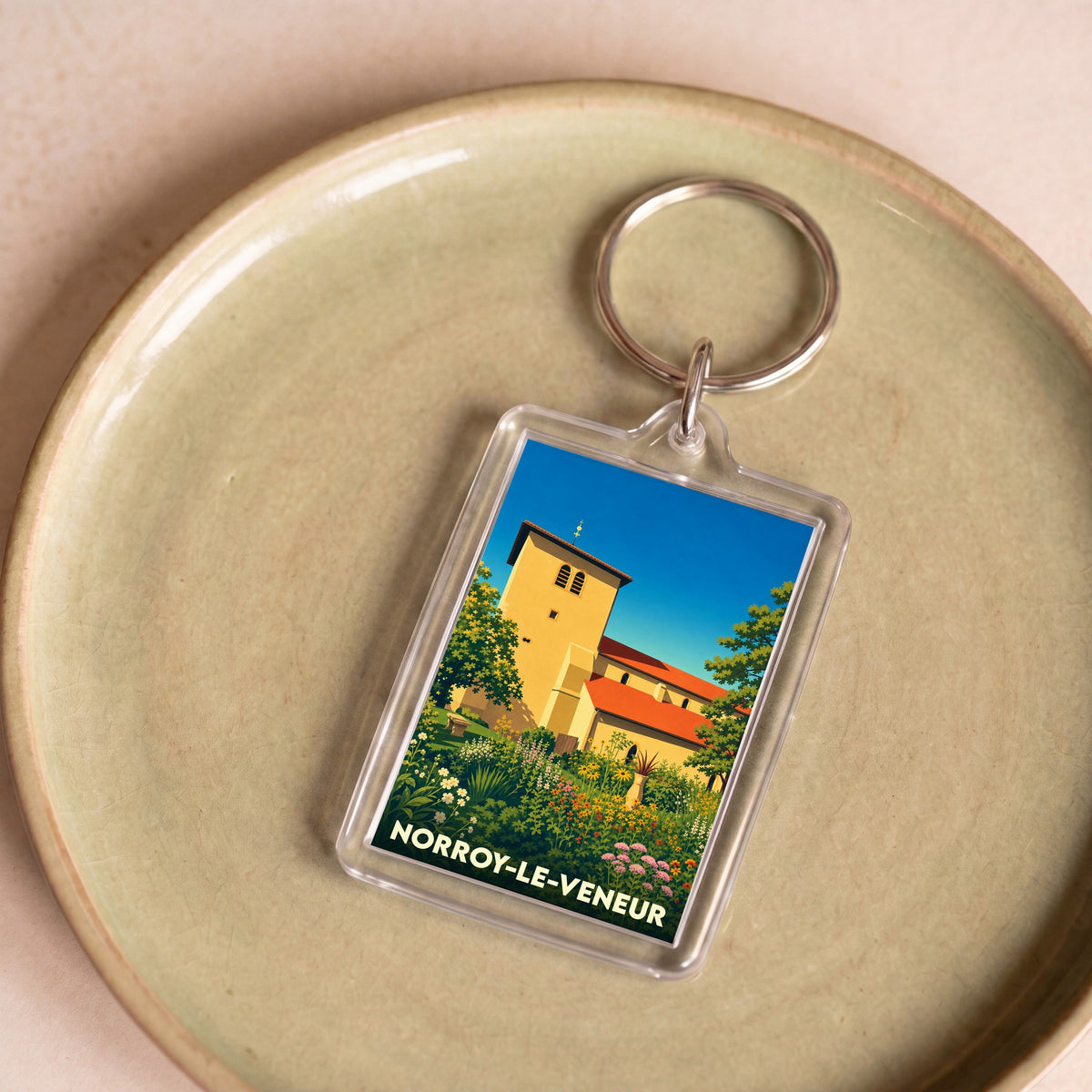 Porte-clés souvenir de la ville de Norroy-le-Veneur avec une illustration colorée et stylisée de son église.