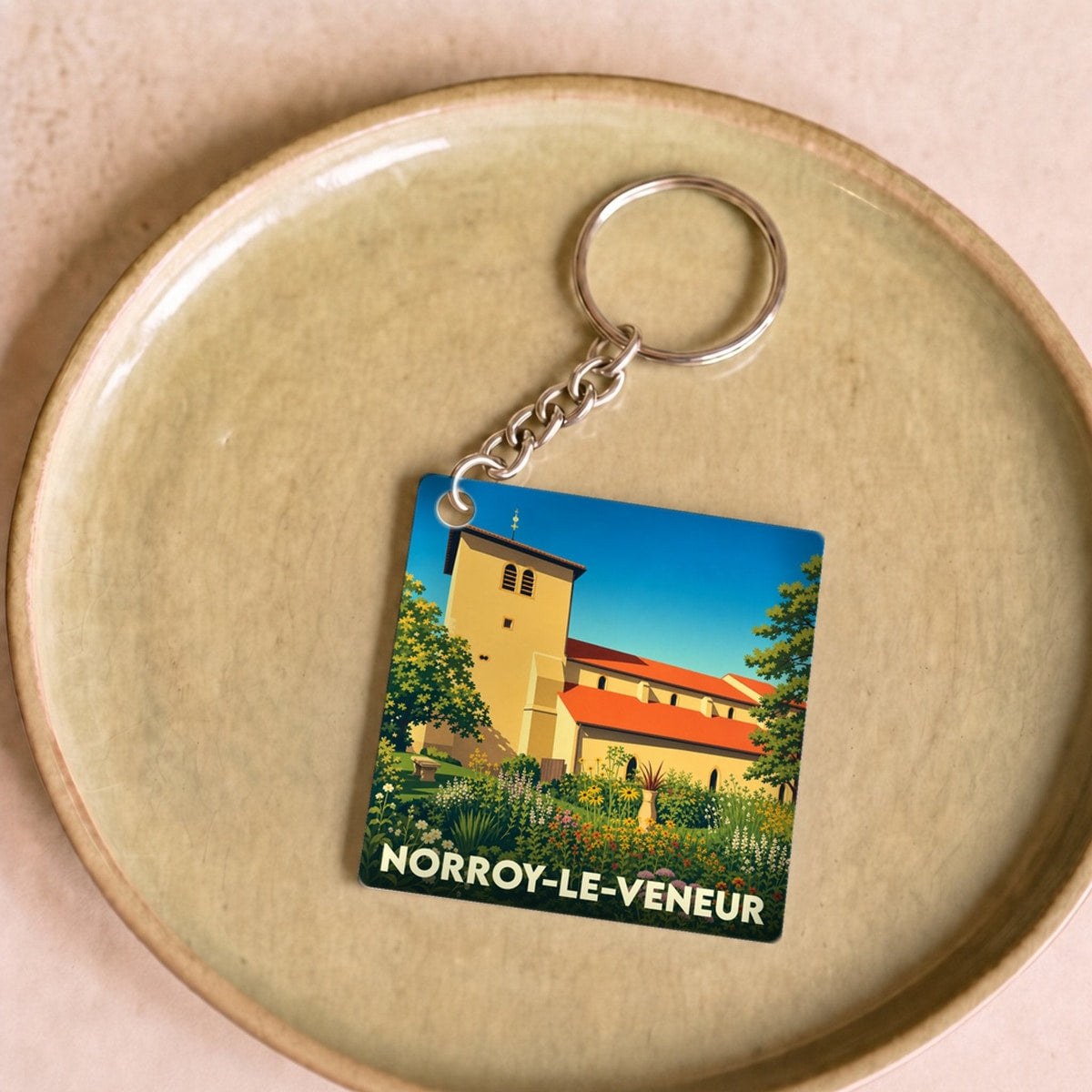 Porte-clés souvenir de la ville de Norroy-le-Veneur avec une illustration colorée et stylisée de son église.