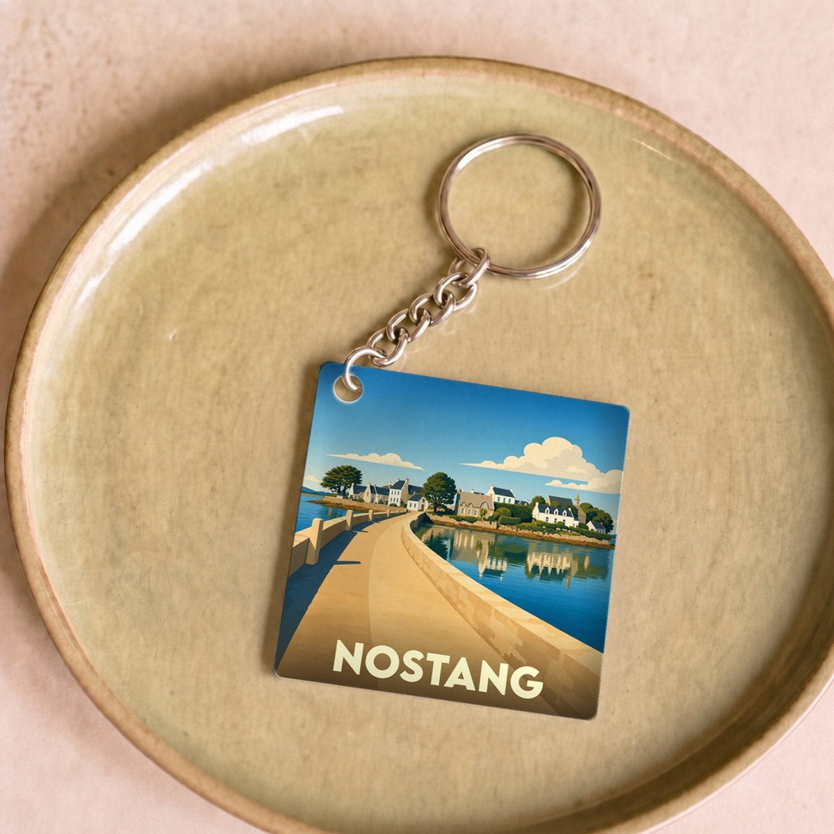 Porte-clés souvenir de la ville de Nostang avec une illustration stylisée.