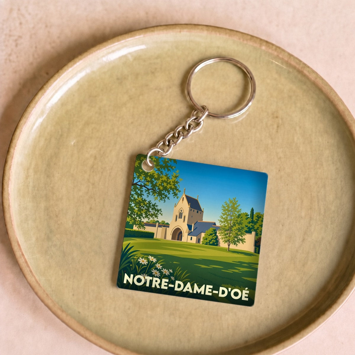 Porte-clés souvenir de la ville de Notre-Dame-d'Oé avec une illustration stylisée.