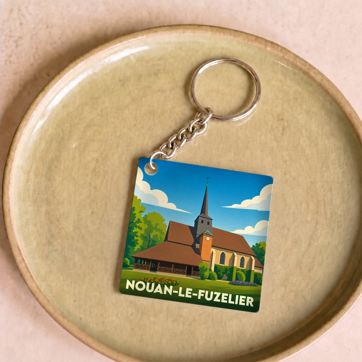 Porte-clés souvenir de la ville de Nouan-le-Fuzelier avec une illustration stylisée d'une église locale.