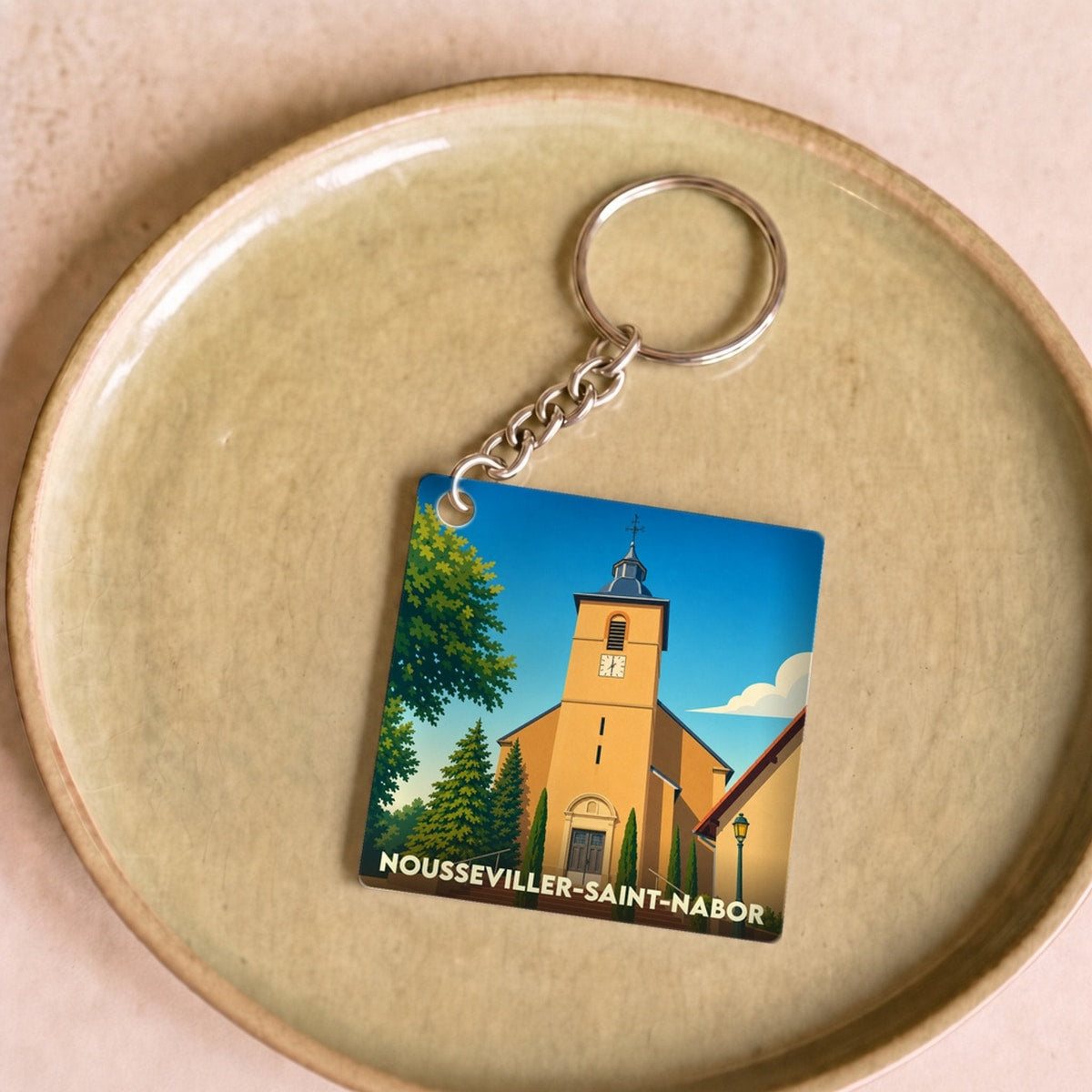 Porte-clés souvenir de la ville de Nousseviller-Saint-Nabor avec une illustration stylisée de son église.