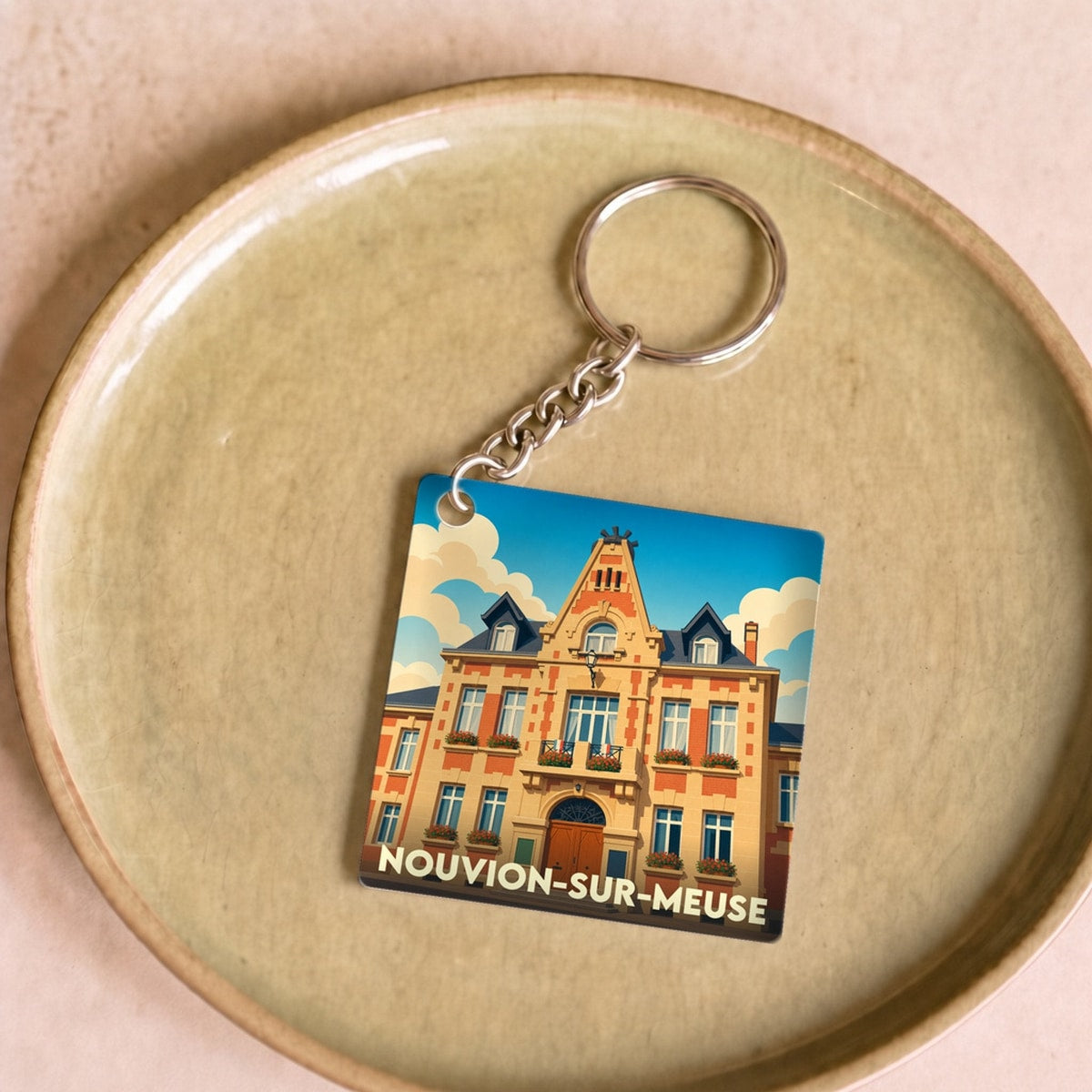 Porte-clés souvenir de la ville de Nouvion-sur-Meuse avec une illustration stylisée de sa mairie.