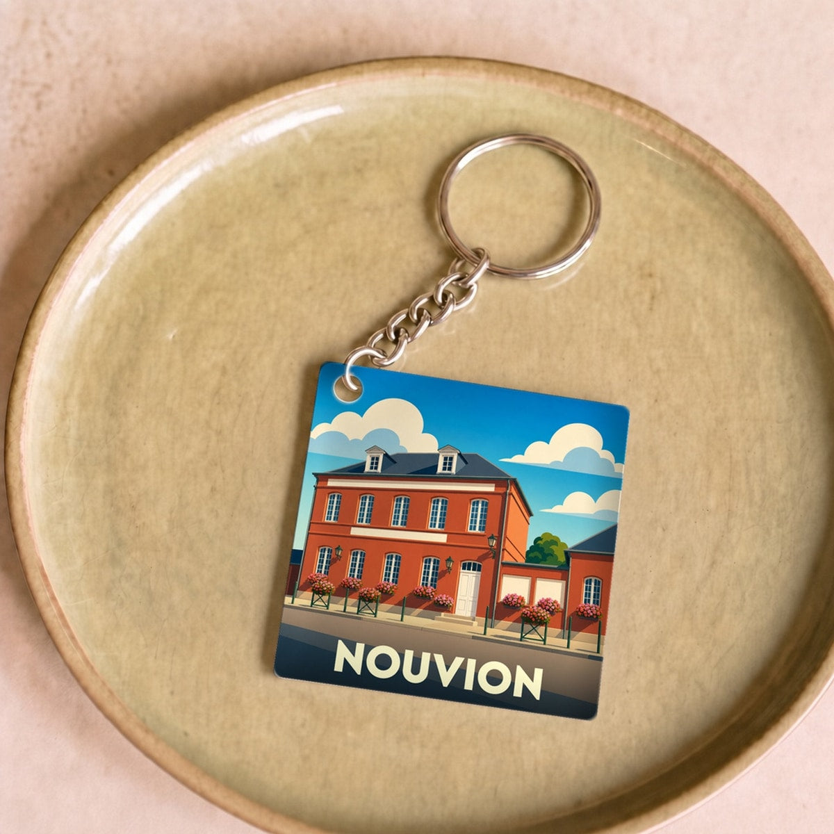 Porte-clés souvenir de la ville de Nouvion avec une illustration stylisée d'un bâtiment historique.