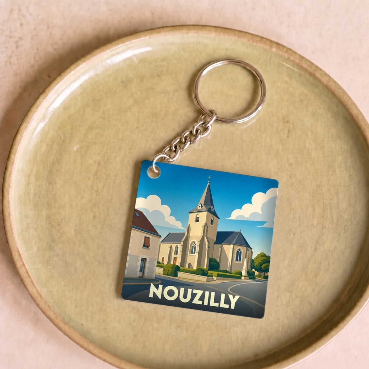 Porte-clés souvenir de la ville de Nouzilly avec une illustration stylisée d'une église sous un ciel bleu.
