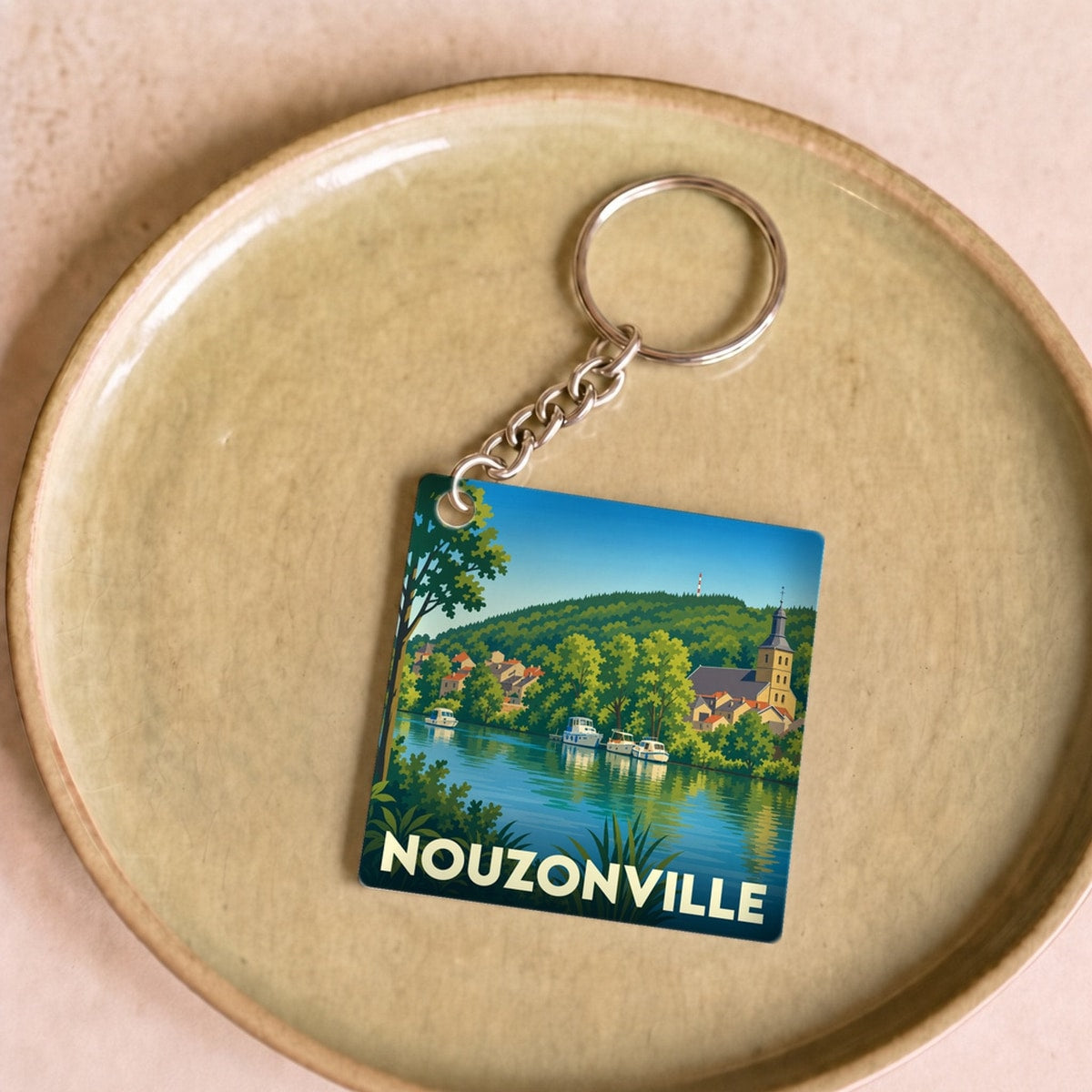 Porte-clés souvenir de la ville de Nouzonville avec une illustration stylisée des bords de Meuse.