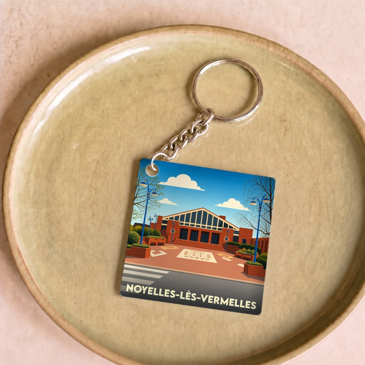 Porte-clés souvenir de la ville de Noyelles-lès-Vermelles avec une illustration stylisée.
