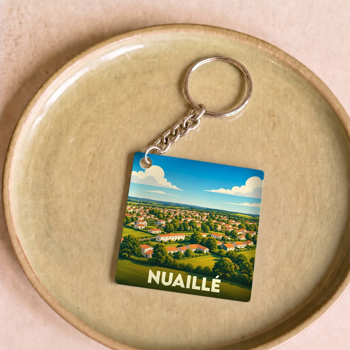 Porte-clés souvenir de la ville de Nuaillé avec une illustration stylisée de son paysage urbain.