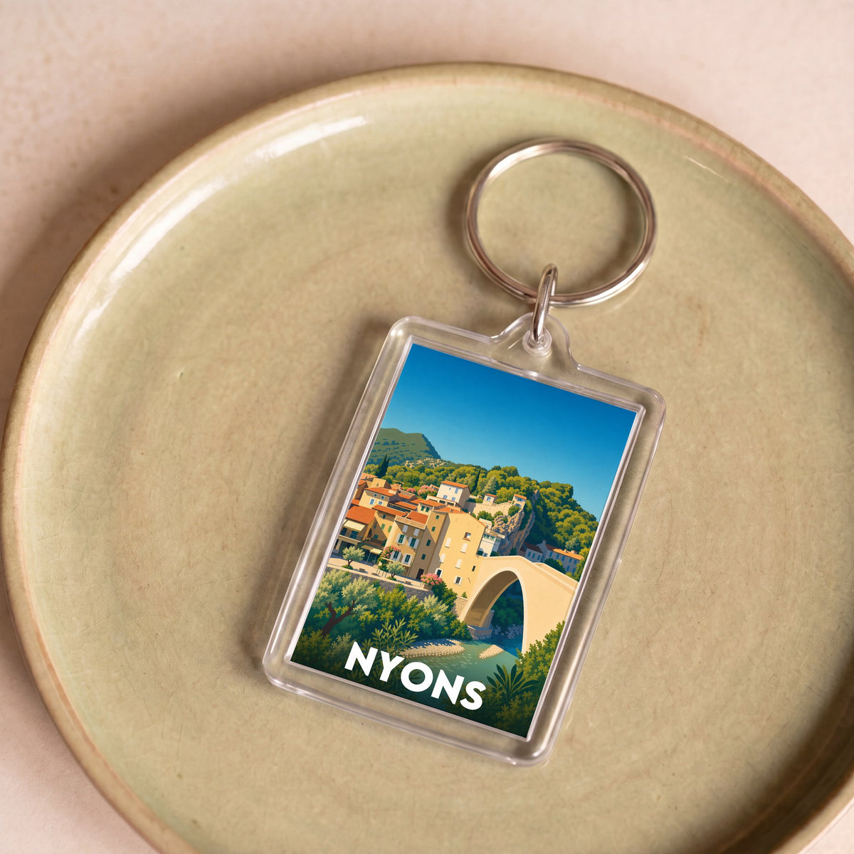 Porte-clés souvenir de la ville de Nyons avec une illustration stylisée.