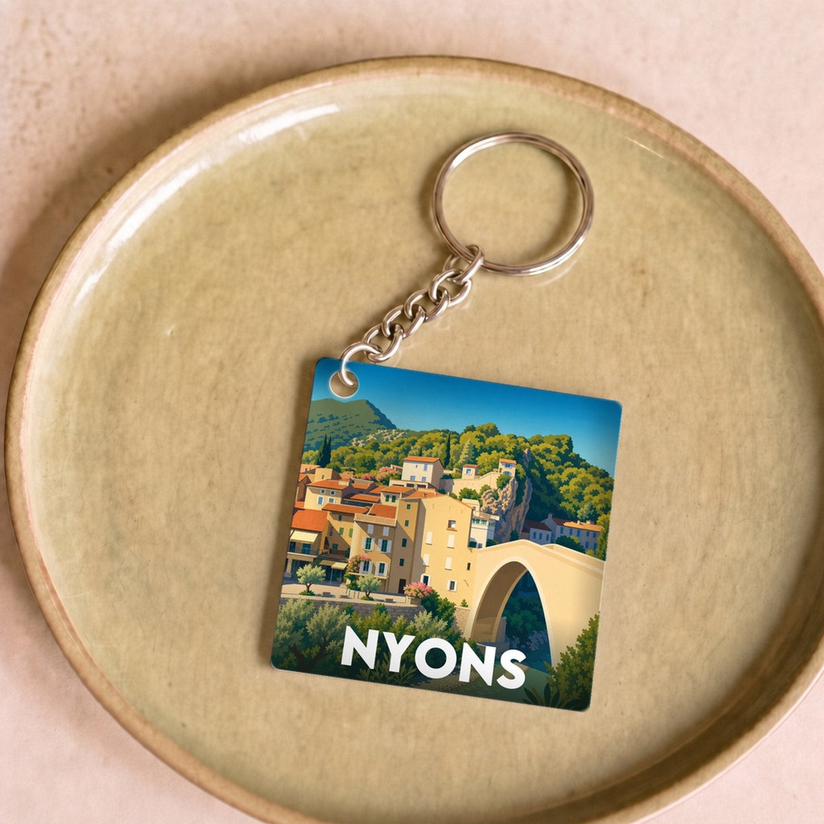 Porte-clés souvenir de la ville de Nyons avec une illustration stylisée.