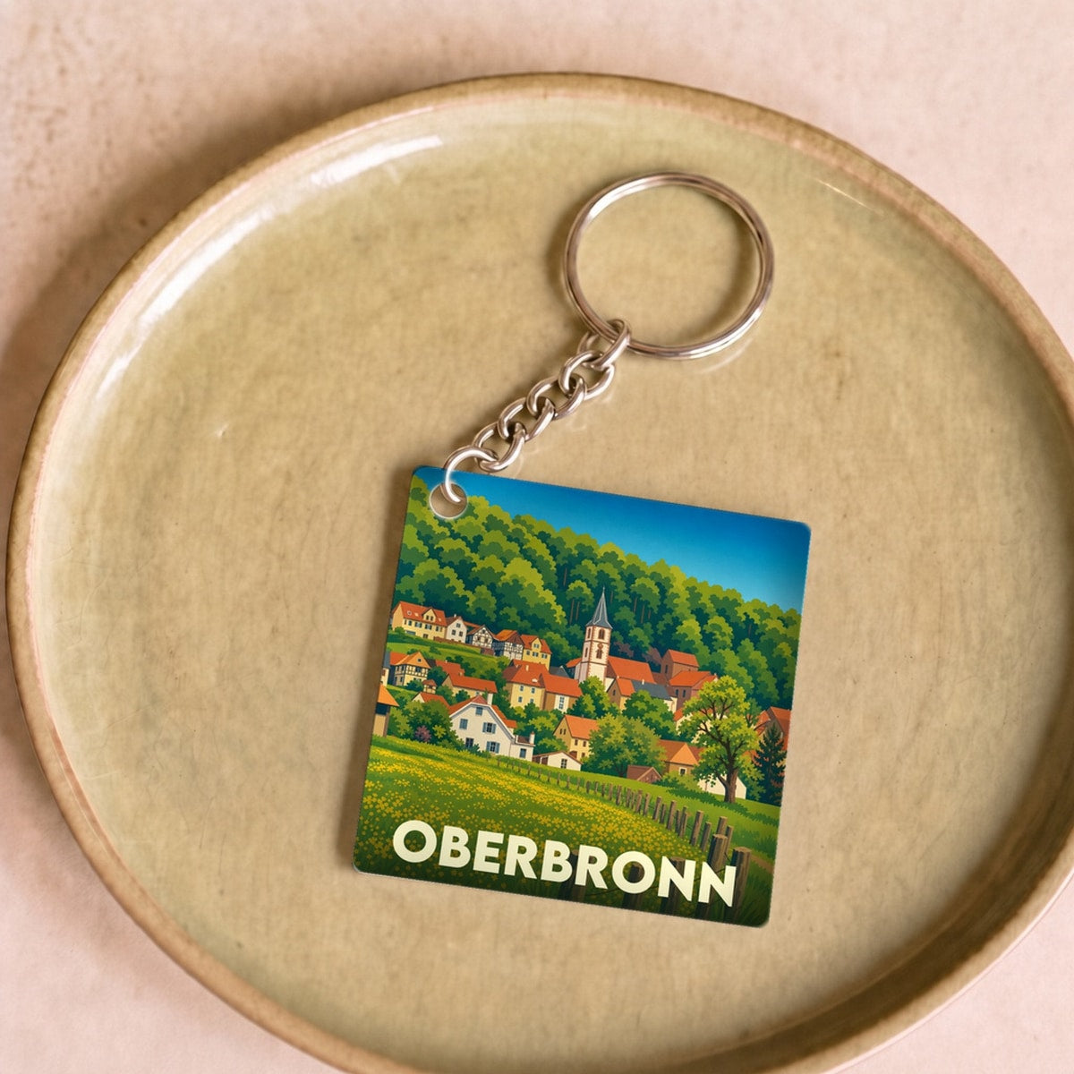 Porte-clés souvenir de la ville d'Oberbronn avec une illustration stylisée d'un paysage alsacien.