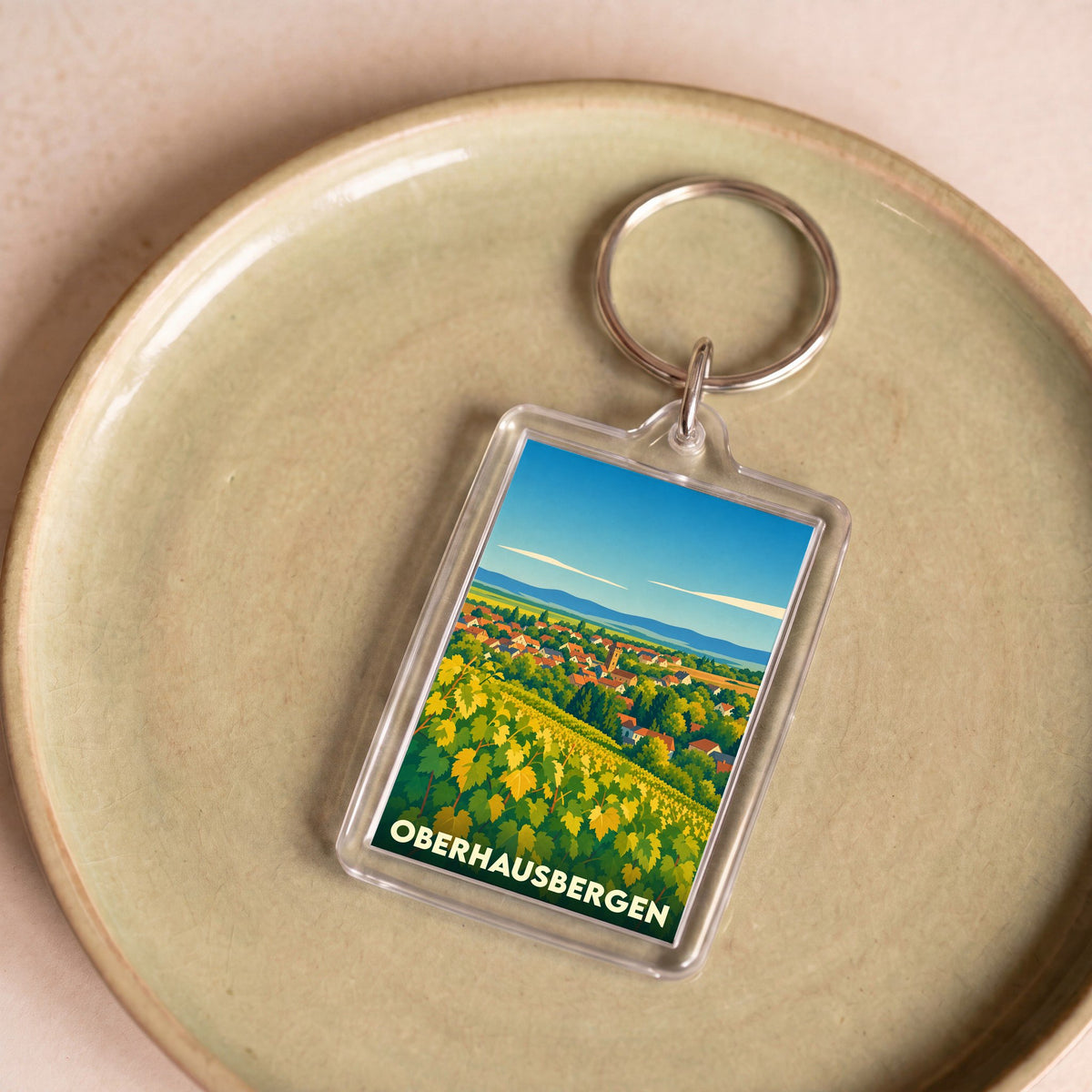 Porte-clés souvenir de la ville de Oberhausbergen avec une illustration stylisée de vignobles et de maisons.