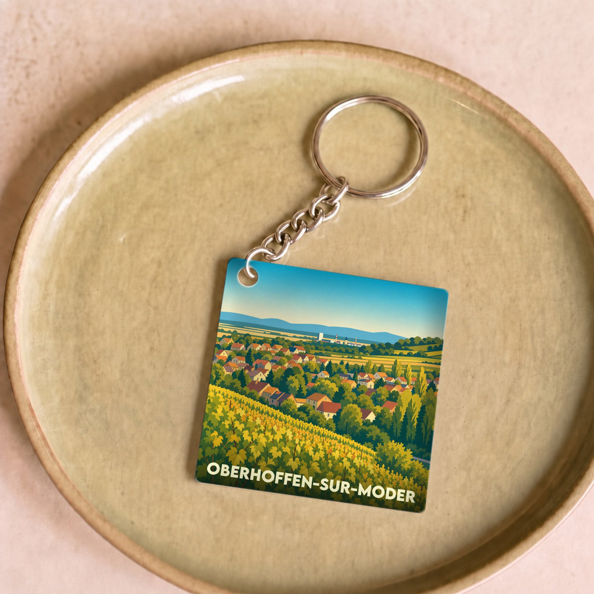 Porte-clés souvenir de la ville d'Oberhoffen-sur-Moder avec une illustration stylisée de vignobles et du village.