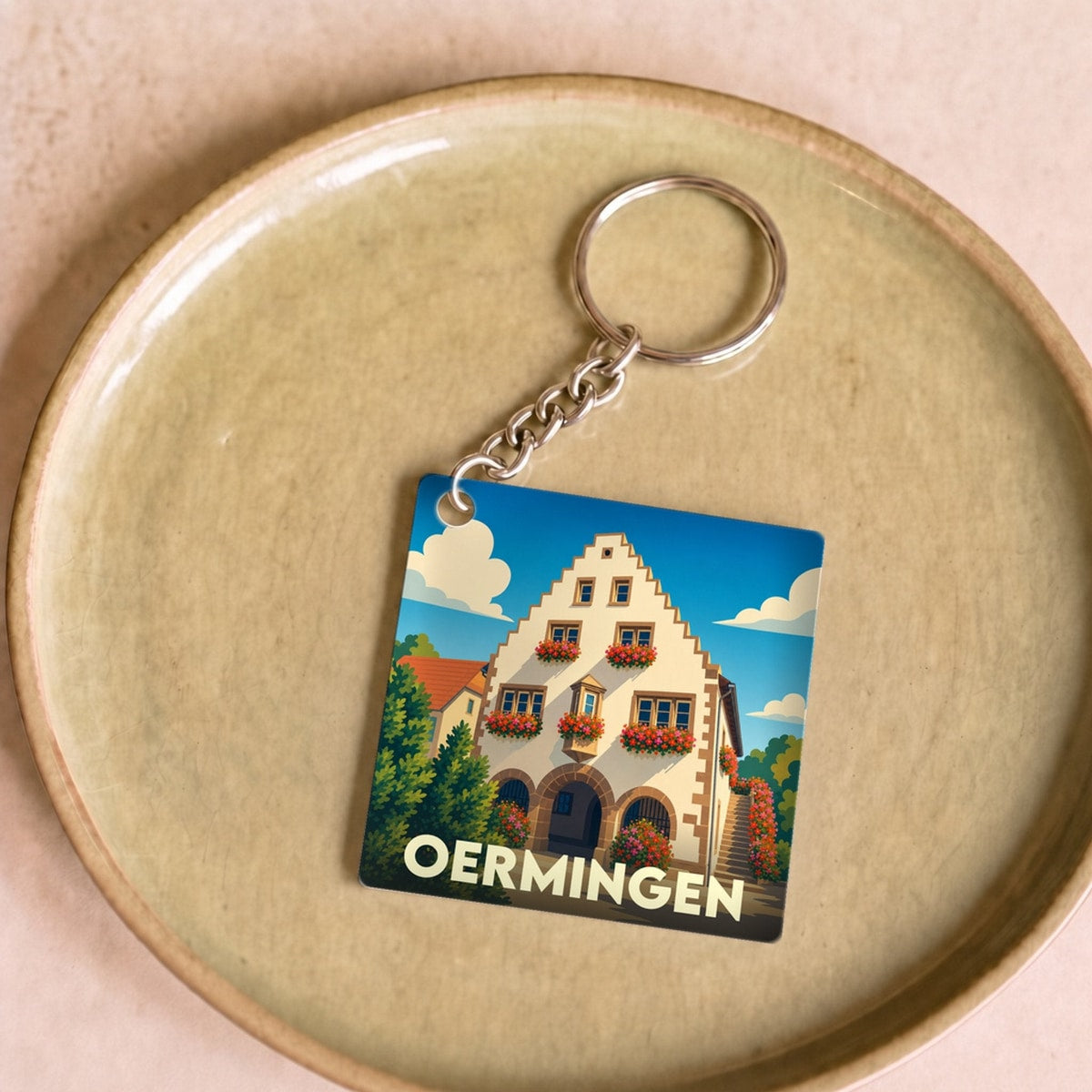 Porte-clés souvenir de la ville de Oermingen avec une illustration stylisée de sa mairie historique.