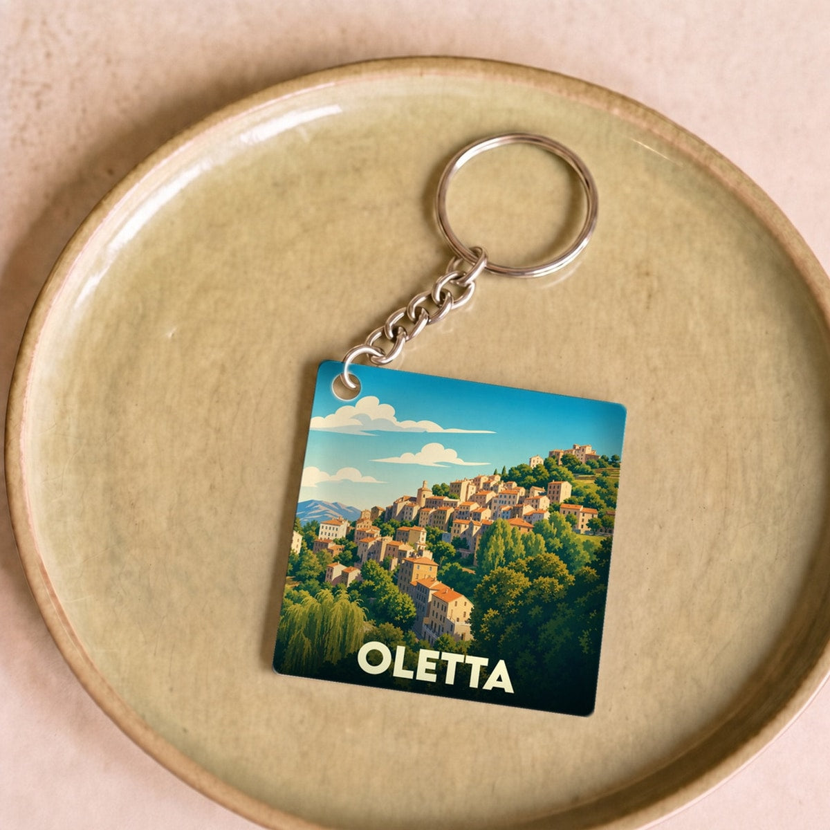 Porte-clés souvenir de la ville de Oletta avec une illustration stylisée d'un village perché.
