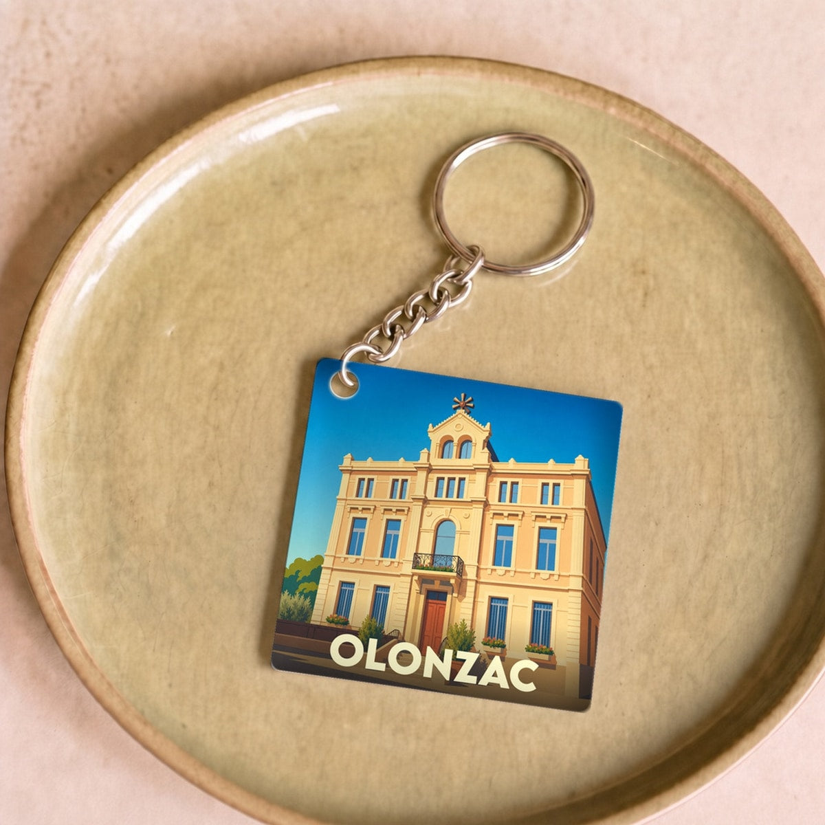 Porte-clés souvenir de la ville d'Olonzac avec une illustration stylisée de sa mairie.