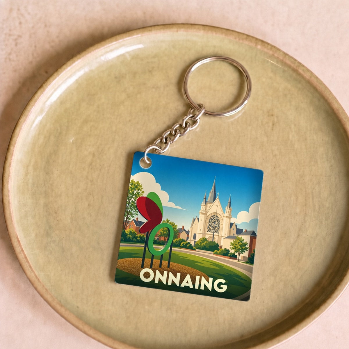 Porte-clés souvenir de la ville d'Onnaing avec une illustration stylisée de son église et d'une sculpture.