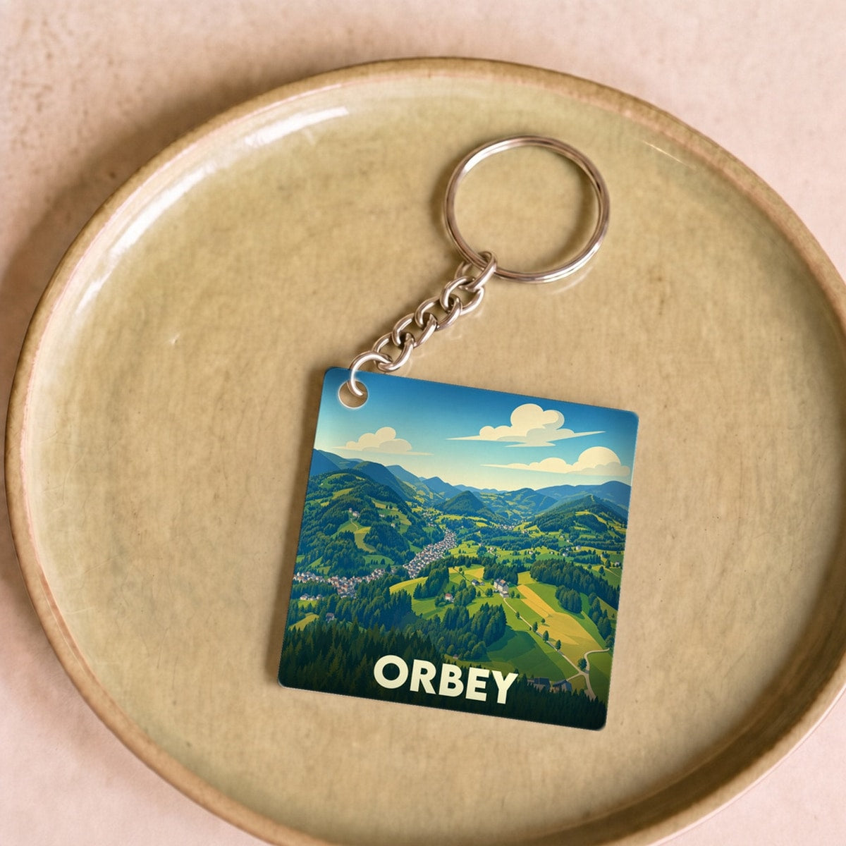 Porte-clés souvenir de la ville d'Orbey avec une illustration stylisée de son paysage montagneux.