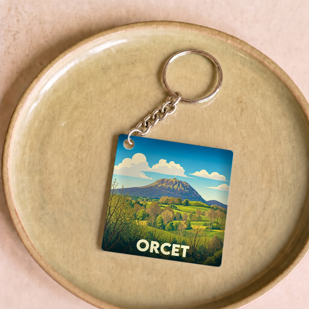 Porte-clés souvenir de la ville d'Orcet avec une illustration stylisée d'un paysage de montagne.