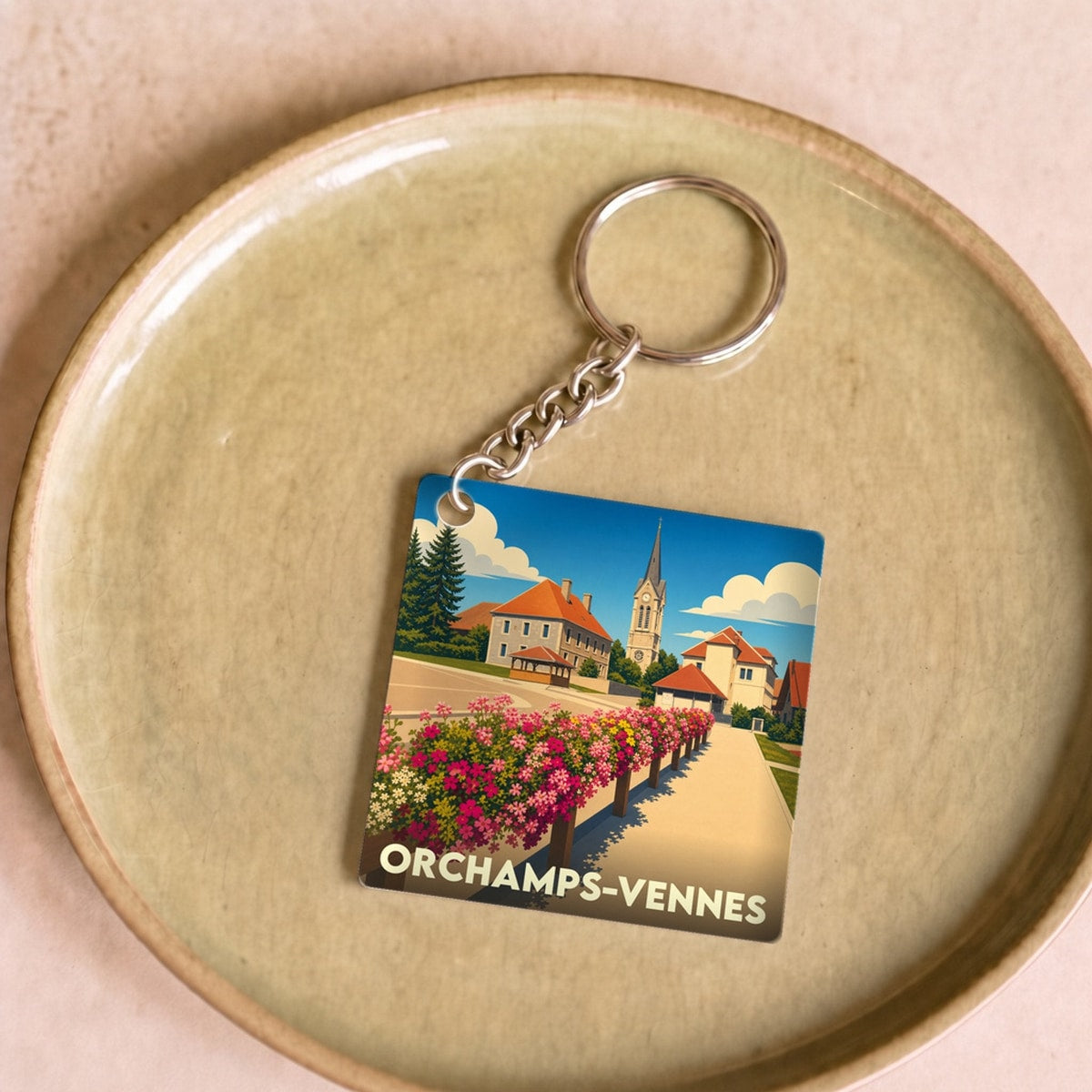 Porte-clés souvenir de la ville d'Orchamps-Vennes avec une illustration stylisée.