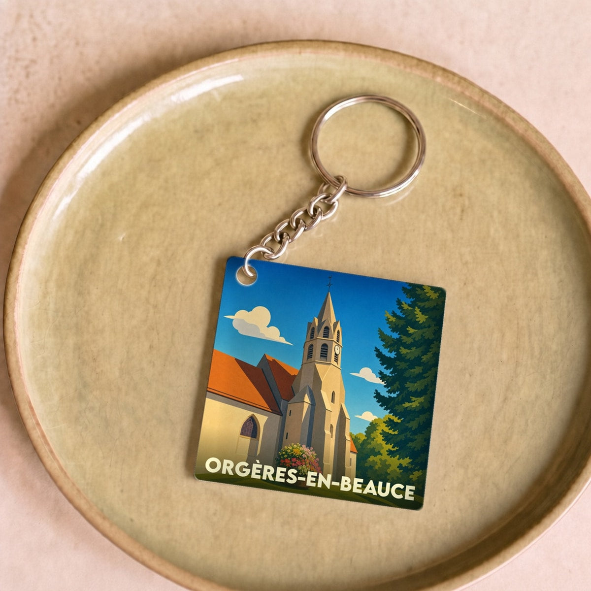 Porte-clés souvenir de la ville de Orgères-en-Beauce avec une illustration stylisée de son église.
