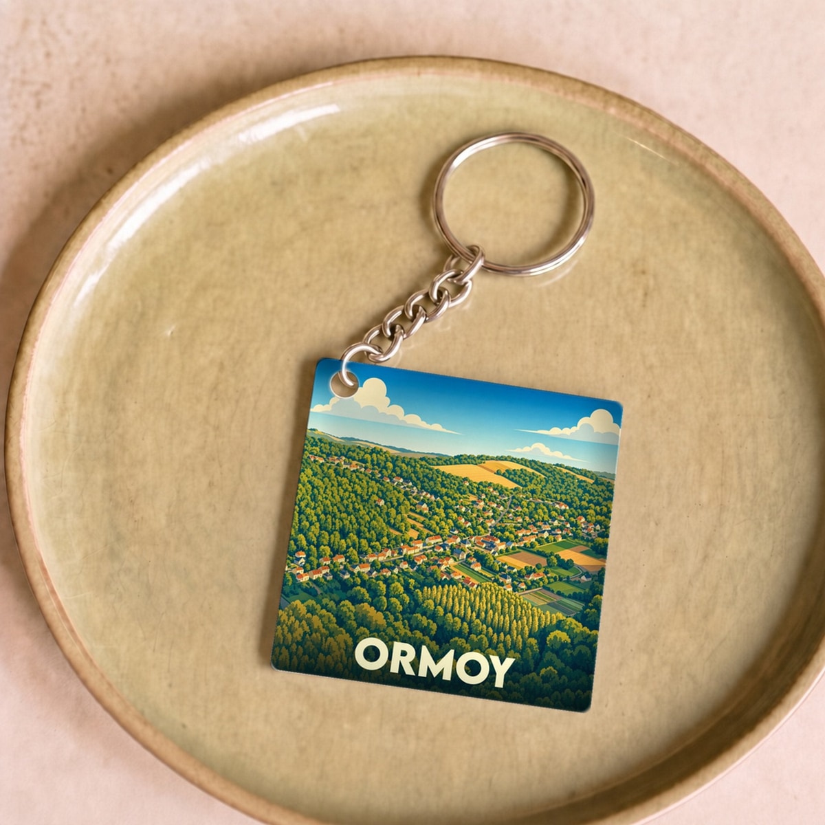 Porte-clés souvenir de la ville d'Ormoy avec une illustration stylisée de son paysage vallonné.